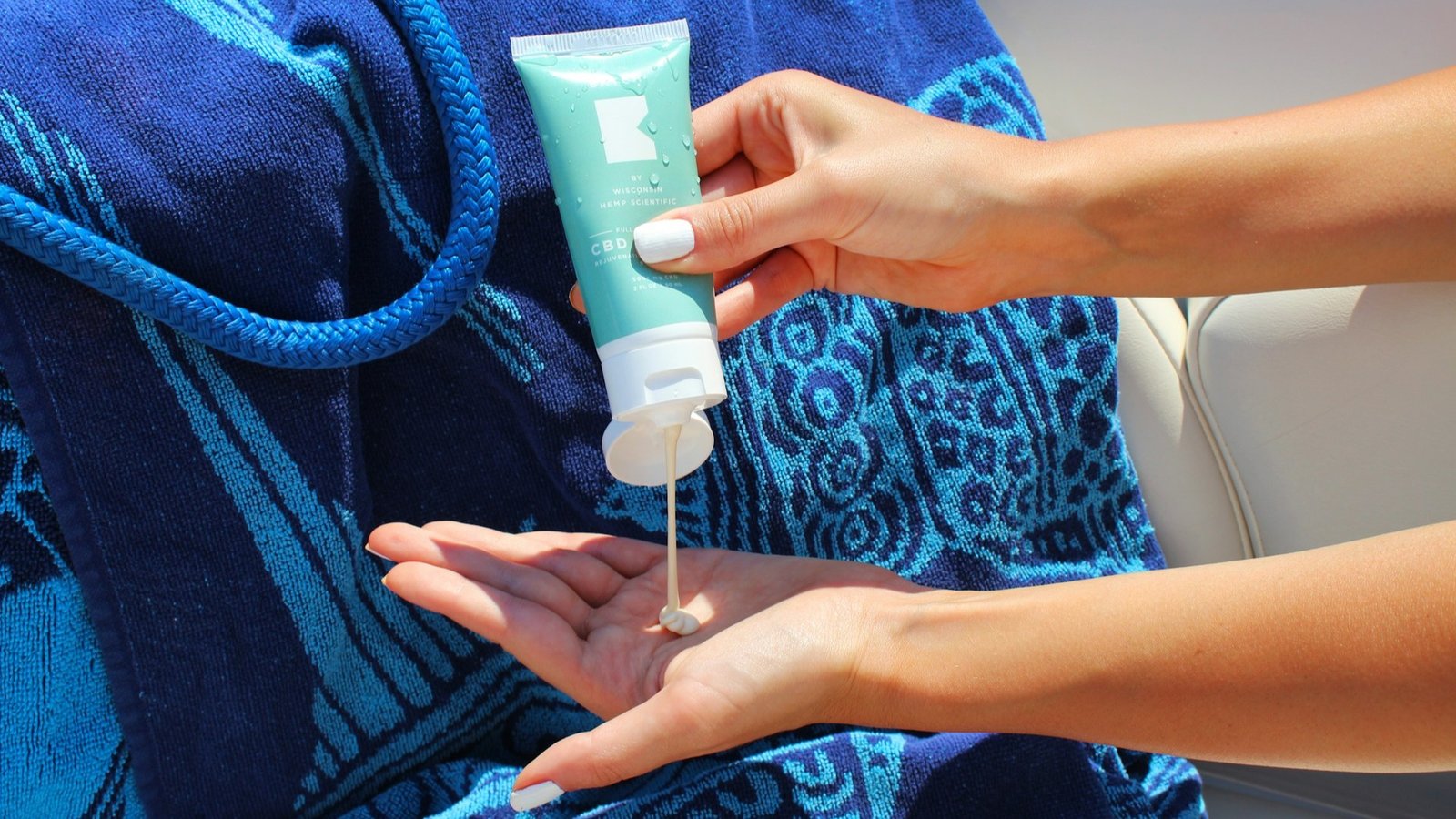 A woman squeezing sunscreen to apply while tanning