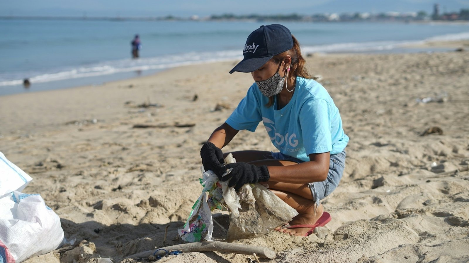 female volunteer cleaning up a beach from plastic pollution