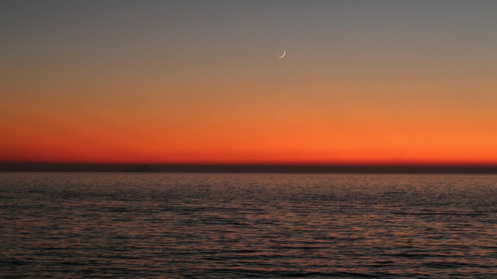 Moon captured during sunset over the ocean